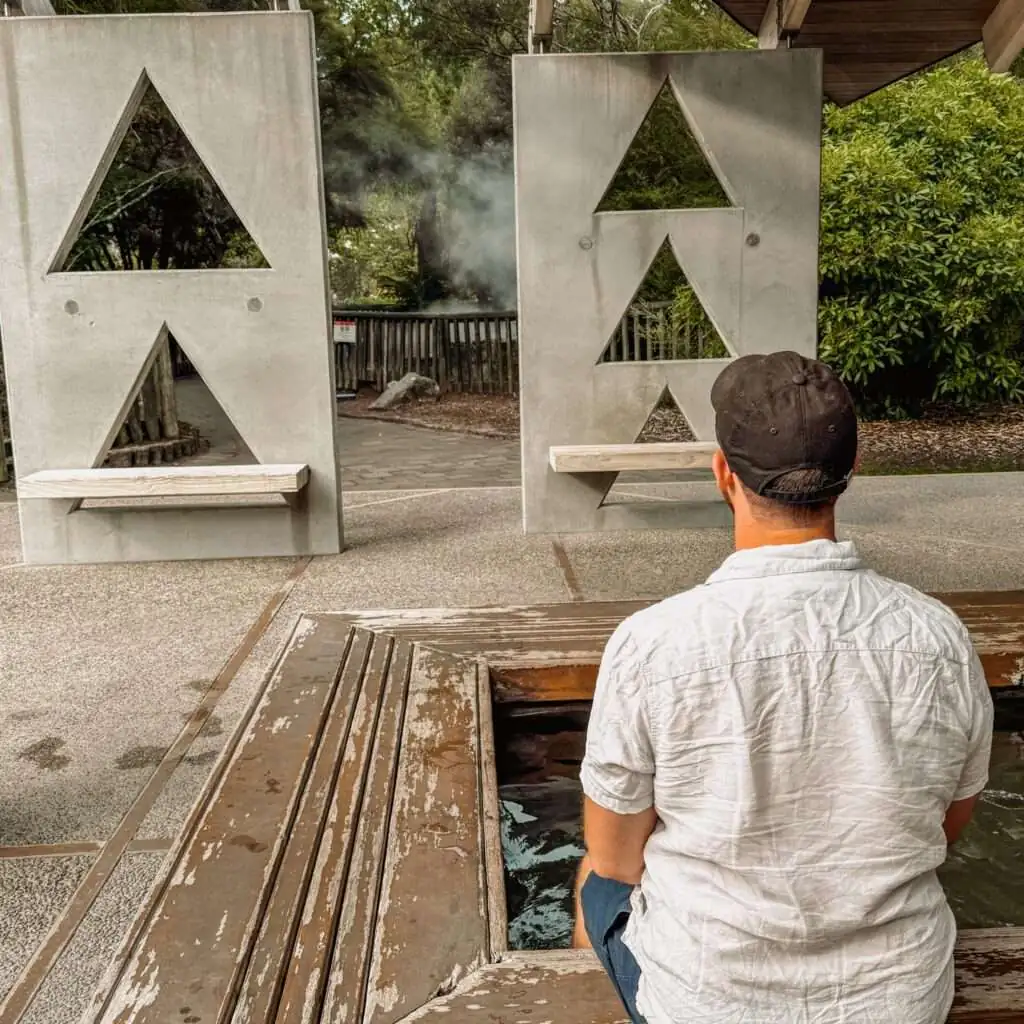 A man with his feet in a public bath as seen in a Rotorua itinerary