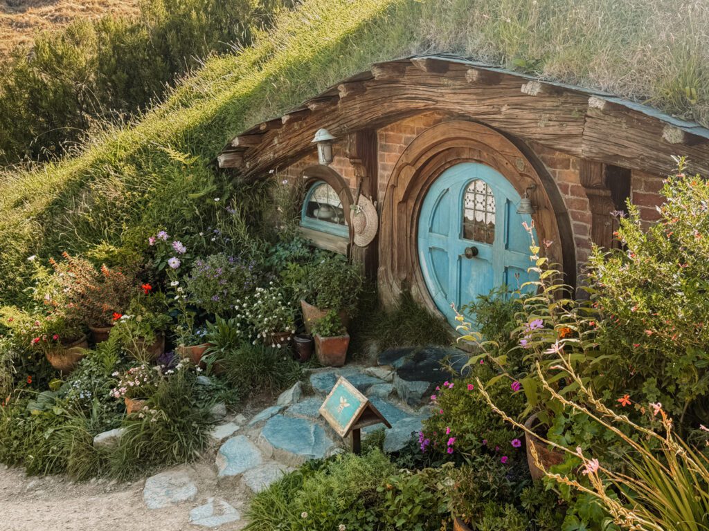 A home built into a hill with a blue door in Hobbiton