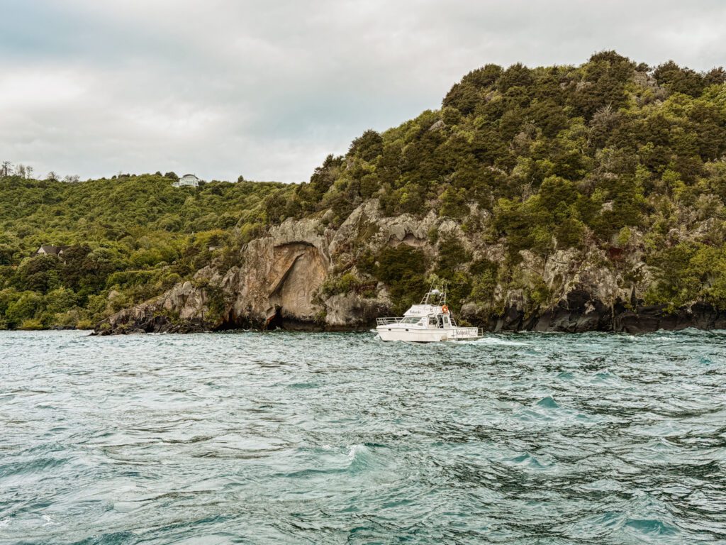 a boat on a lake against a rock cliff shore in Taupo