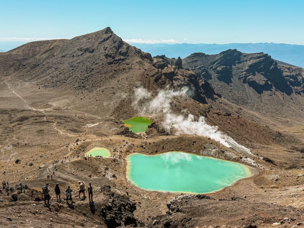 Turquoise pools nestled into the valley of a red rocky mountain outside of Taupo