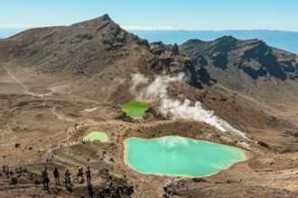Turquoise pools nestled into the valley of a red rocky mountain outside of Taupo on the North Island as one of the top things to do in New Zealand