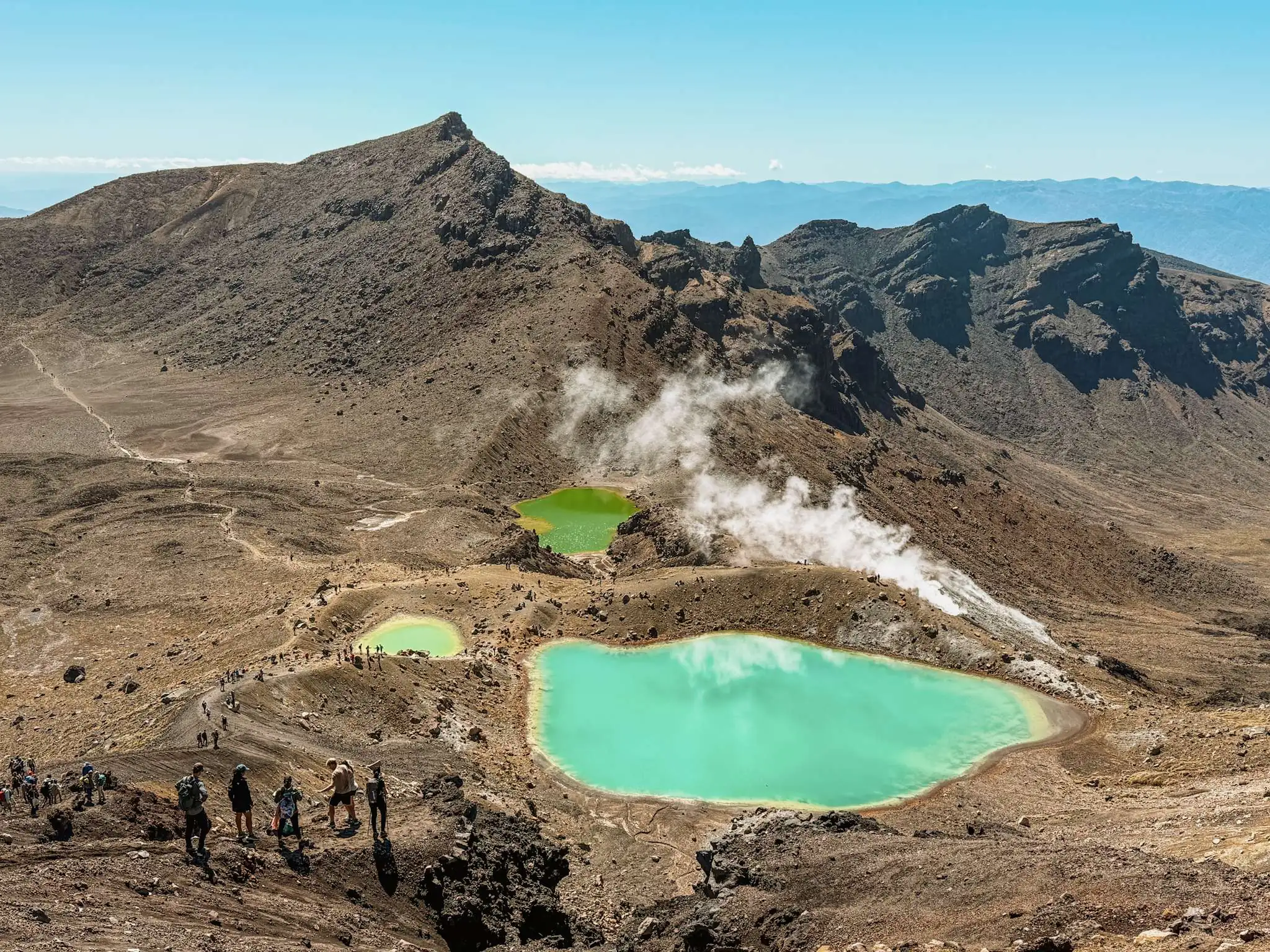 Turquoise pools nestled into the valley of a red rocky mountain outside of Taupo on the North Island as one of the top things to do in New Zealand