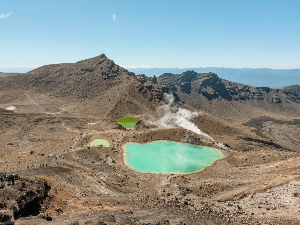 Turquoise pools nestled into the valley of a red rocky mountain outside of Taupo