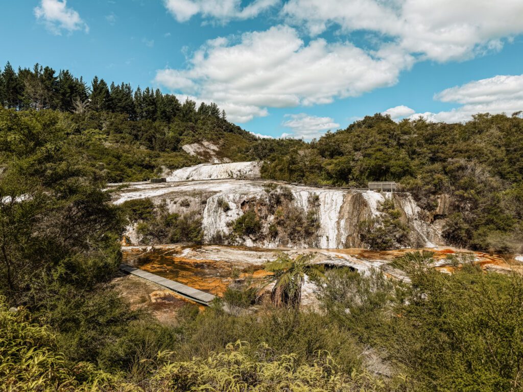 A waterfall flowing down a red rock in a forest in Taupo