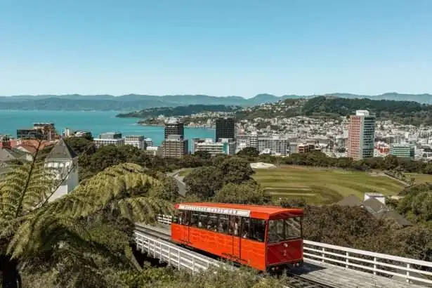 A red cable car going up a hill with a bay in the background - Wellington itinerary