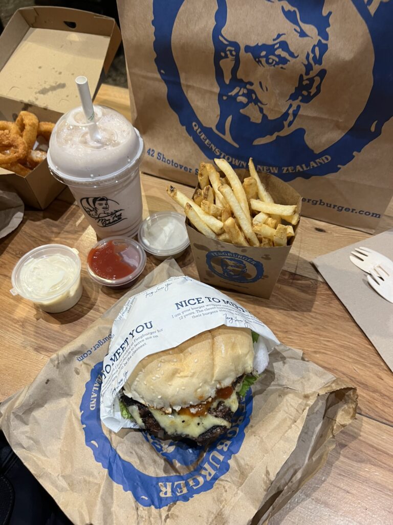 A burger, fries, and milkshake on a table from a restaurant when visiting queenstown