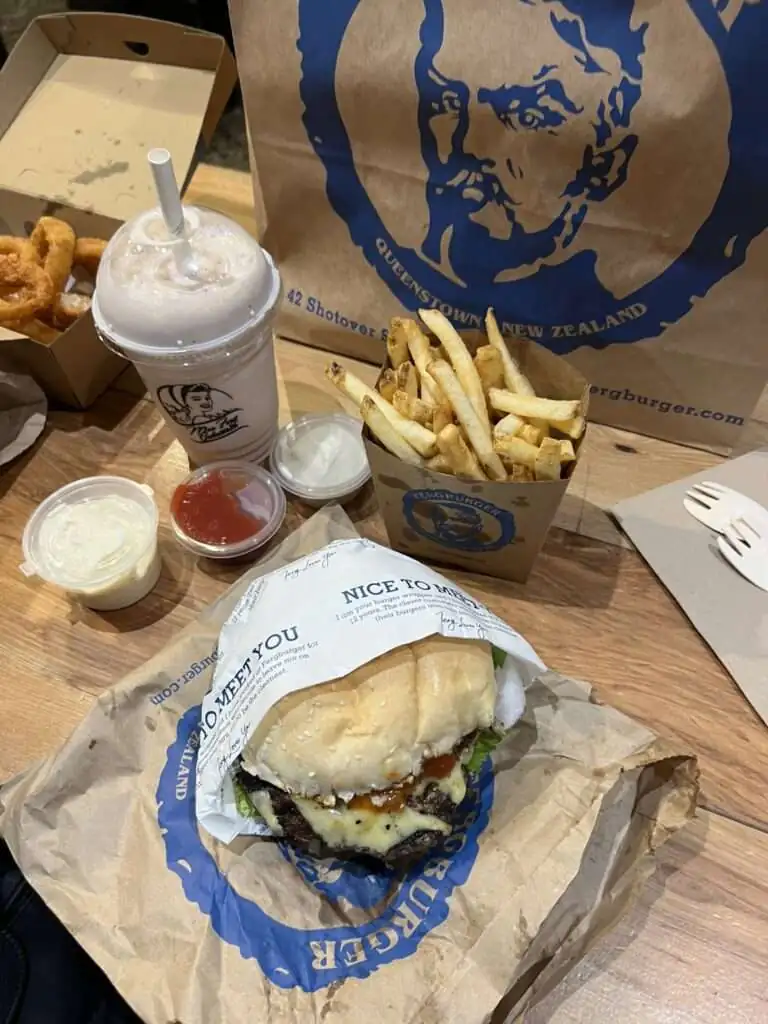 A burger, fries, and milkshake on a table from a restaurant when visiting queenstown
