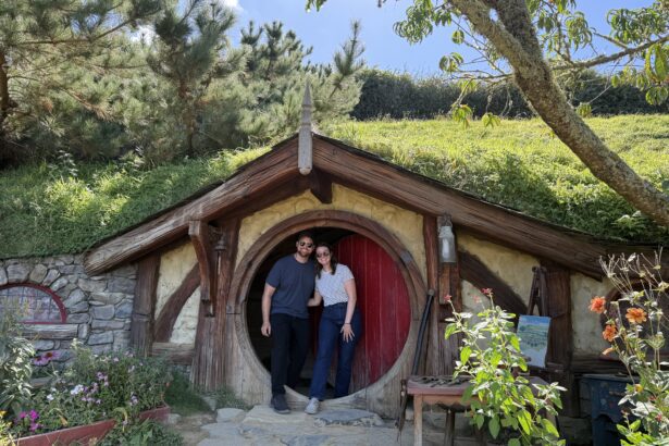 Two people standing in front of a red door to a home built into a hill