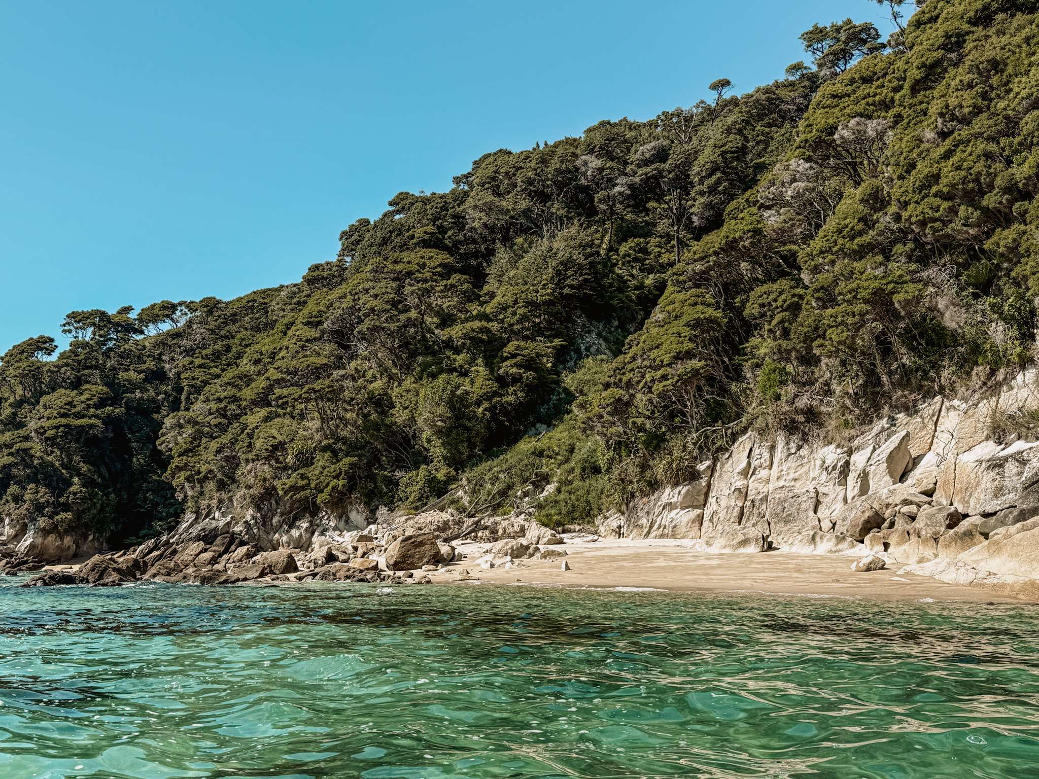 The clear turquoise waters, white sand beaches, and hills full of forests of Abel Tasman National Park