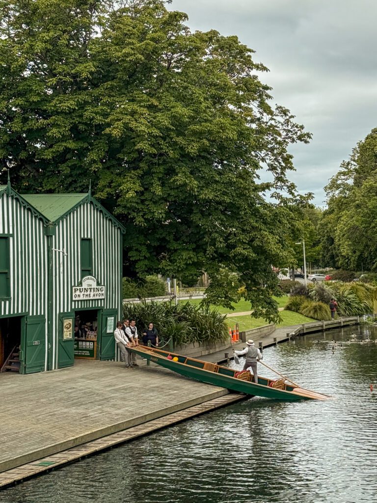 People putting a canoe into a river for tourists to ride on when in Christchurch for a trip between Queenstown and Christchurch