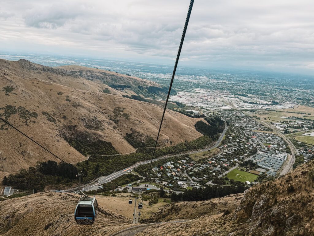 View looking down on a gondola going above a town that can be experienced in Christchurch on the trip between Queenstown and Christchurch