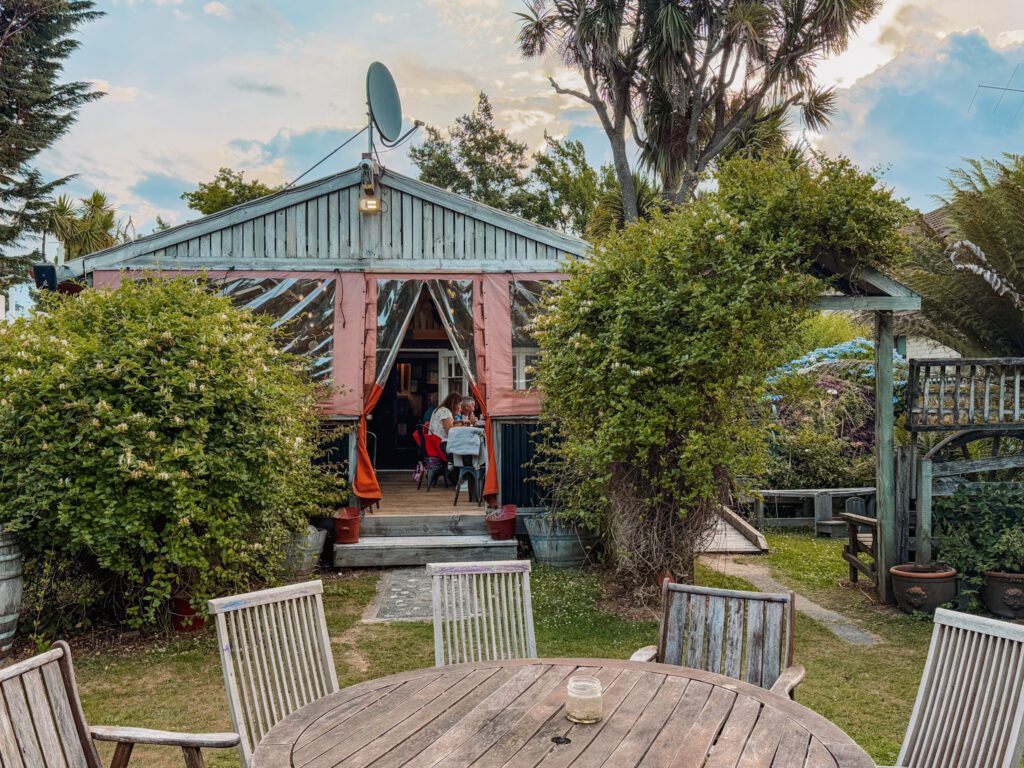 The backyard of a house with a round wood table outside of Fiordland National Park