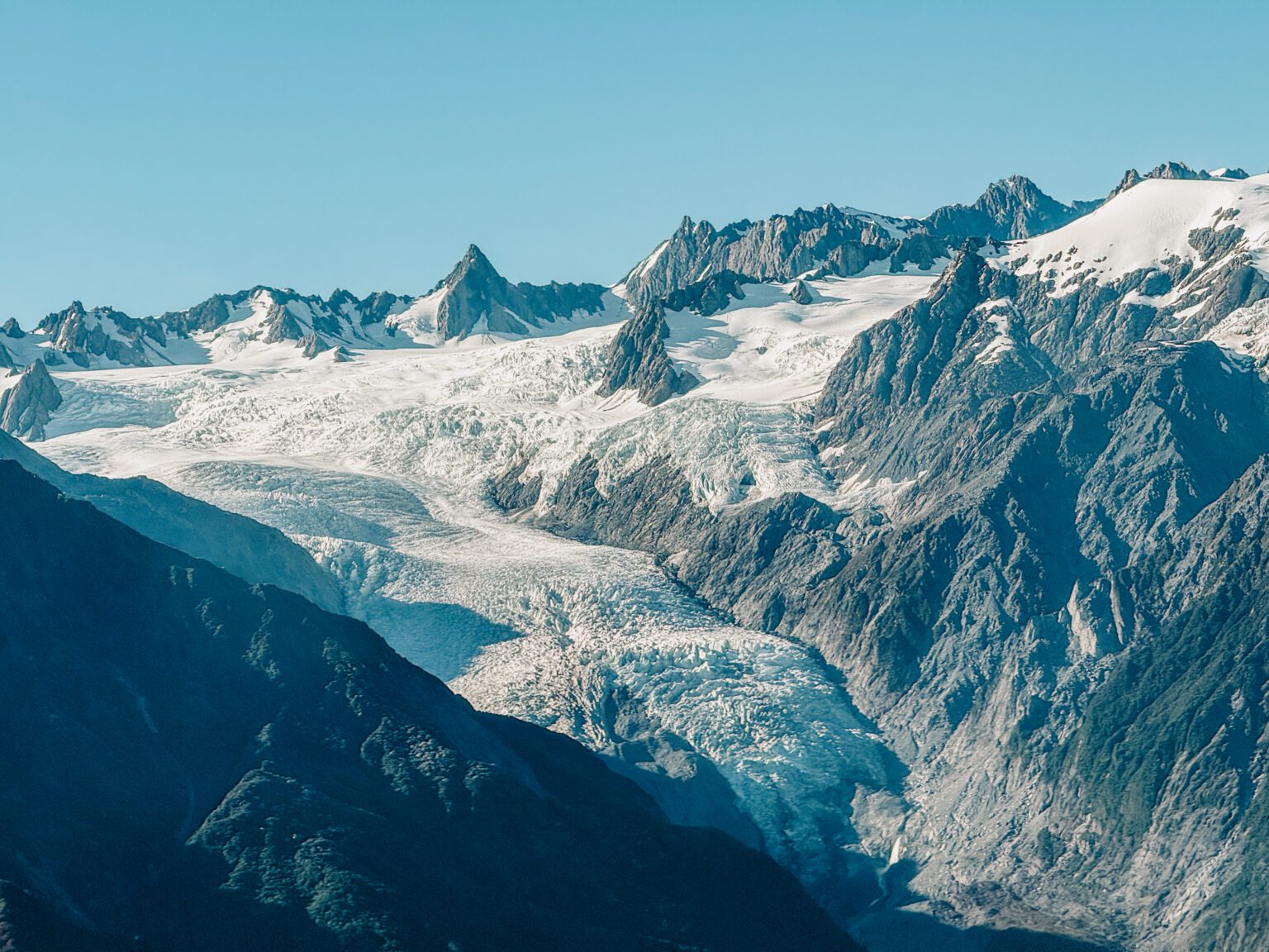 The top of a glacier flowing through mountains as seen from a helicopter on the West Coast of New Zealand
