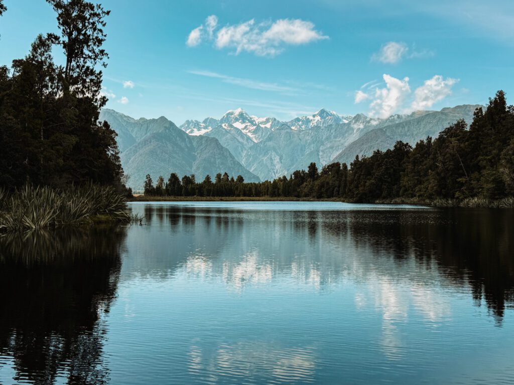 A lake that reflects the surrounding mountains in the West Coast of New Zealand