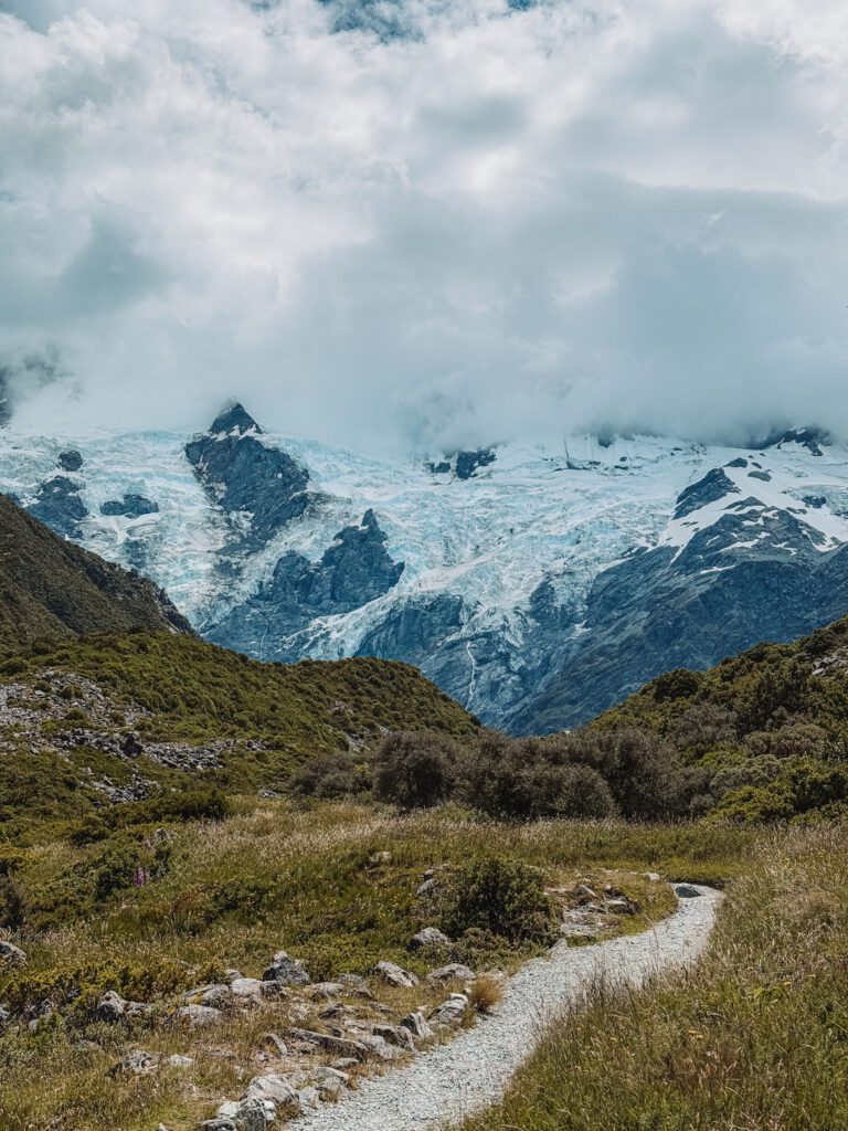 A trail leading to a mountain covered in snow in a park between Queenstown and Christchurch