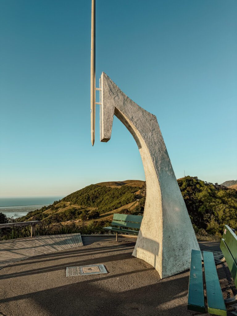 A large monument that looks like the point of a drawing compass on the top of a hill