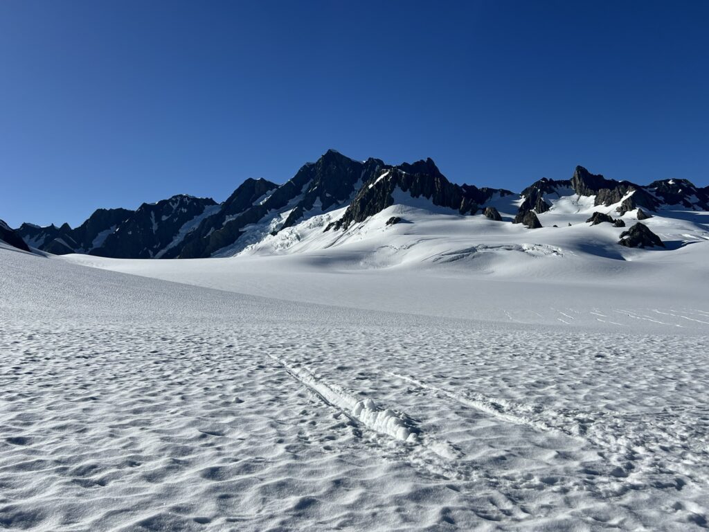 A snowy field with mountains in the background at the top of the Southern Alps