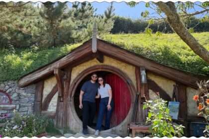 Two people standing in front of a red door to a home built into a hill