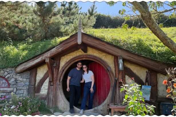 Two people standing in front of a red door to a home built into a hill