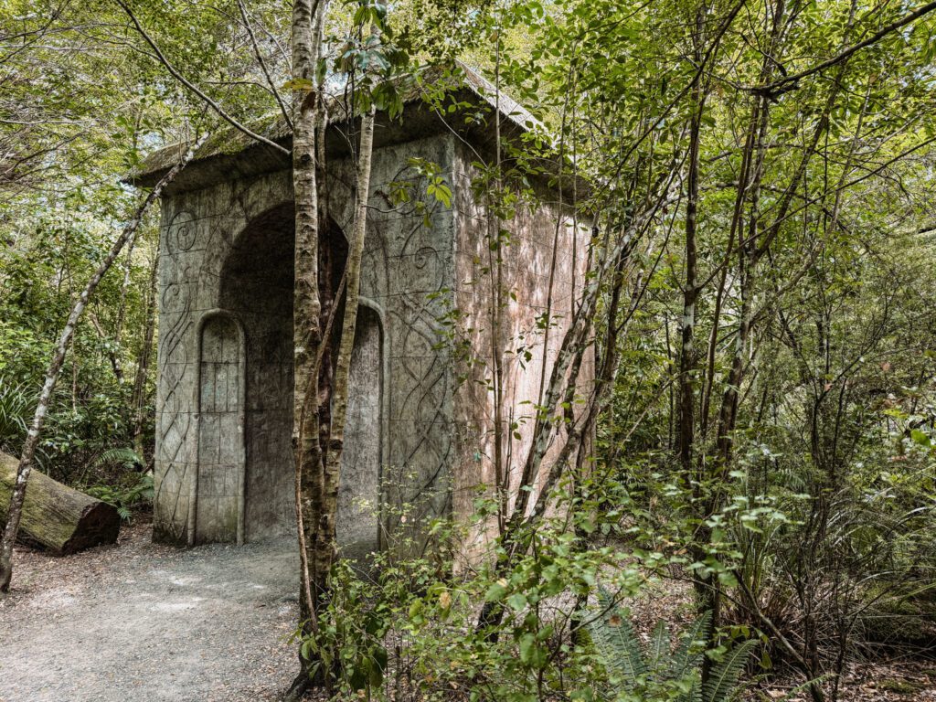 A large white stone arch in a forest used as one of the filming locations in the Lord of the Rings
