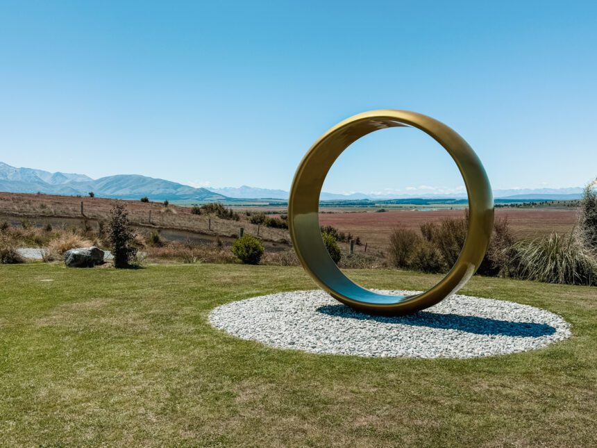 A large gold ring on a hill in front of a field used as one of the filming locations in the Lord of the Rings