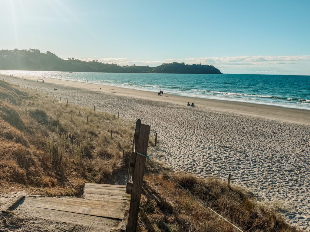 White sand beach in front of turquoise water outside of Auckland