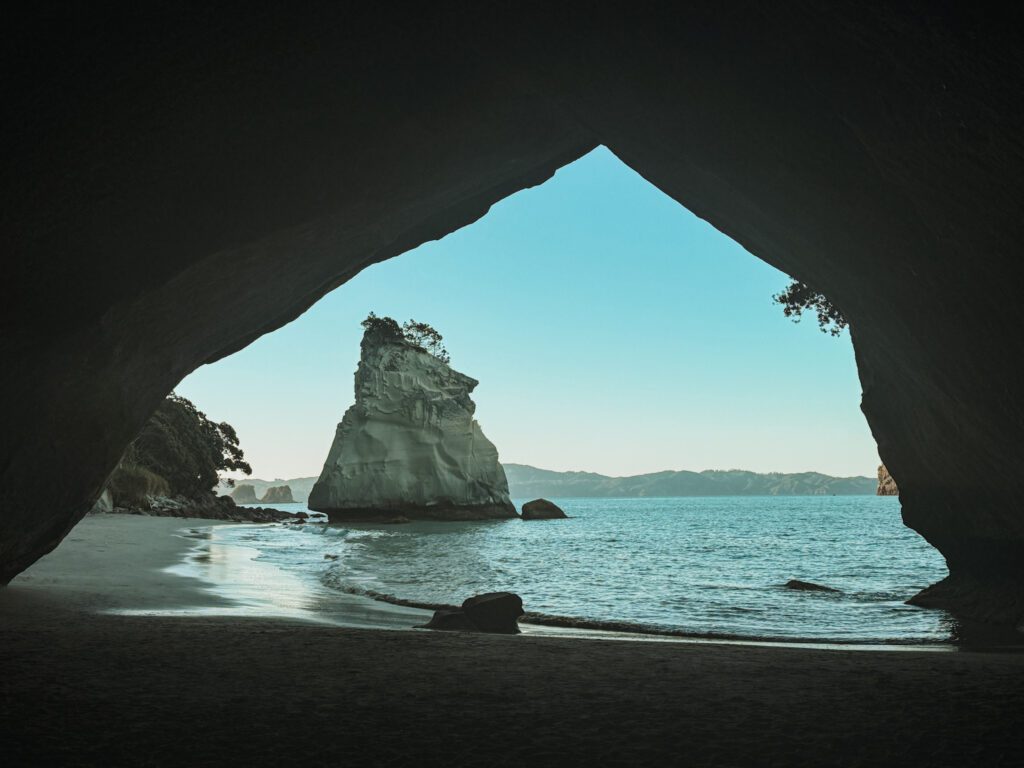 A view through a cave of a rock formation in the water of the Coromandel Peninsula
