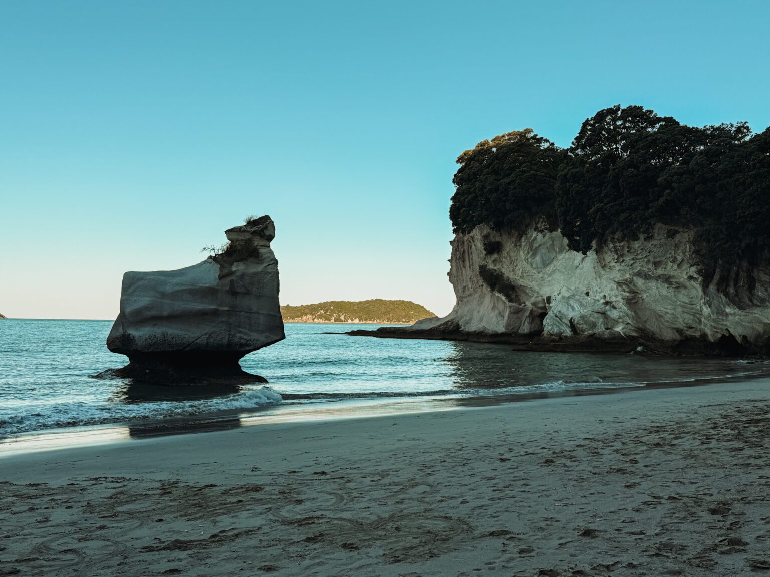 A large rock and cliffs going into the ocean in the Coromandel Peninsula