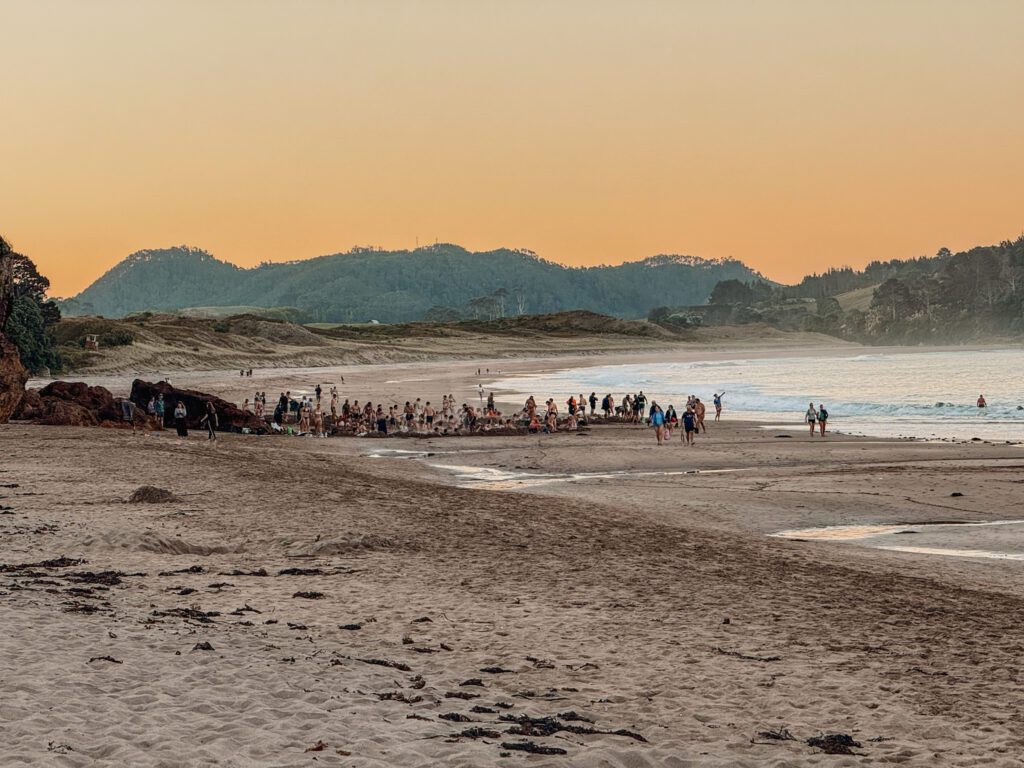 A group of people standing on a beach in the distance on the Coromandel Peninsula