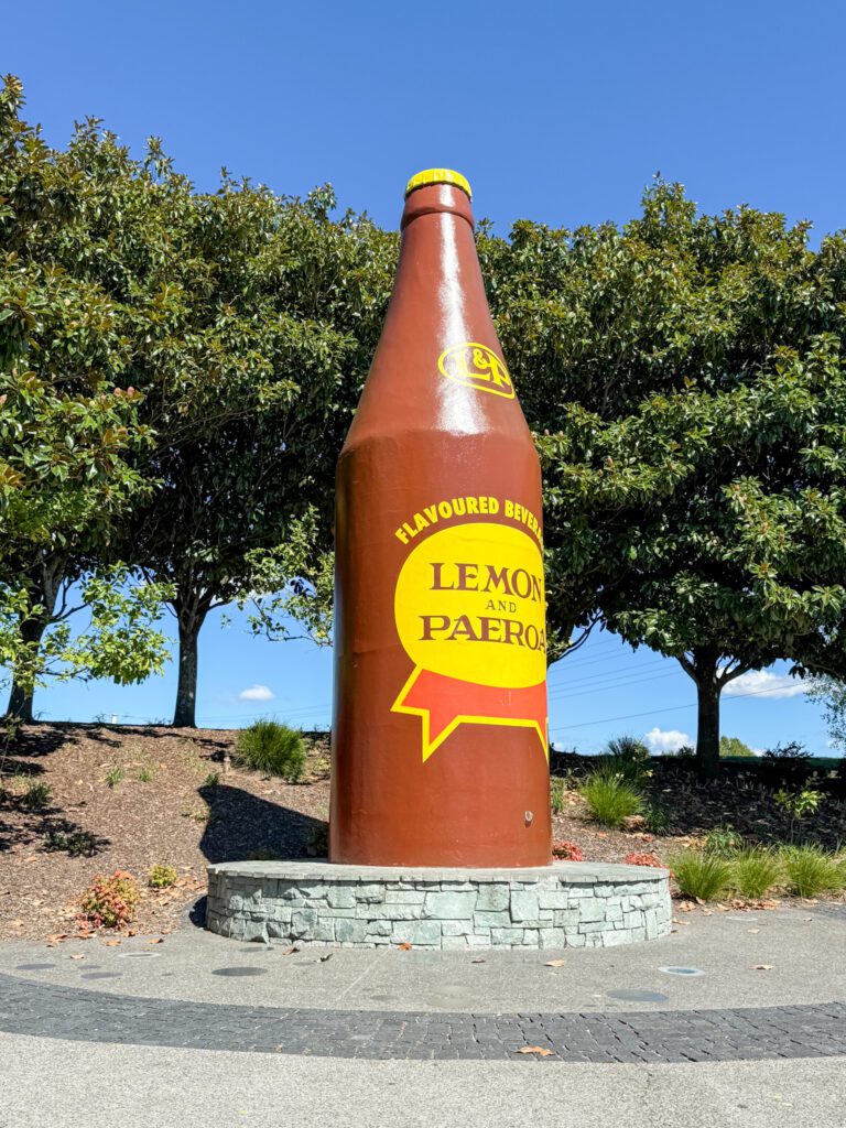A large soda bottle statue on the side of a road in the Coromandel Peninsula