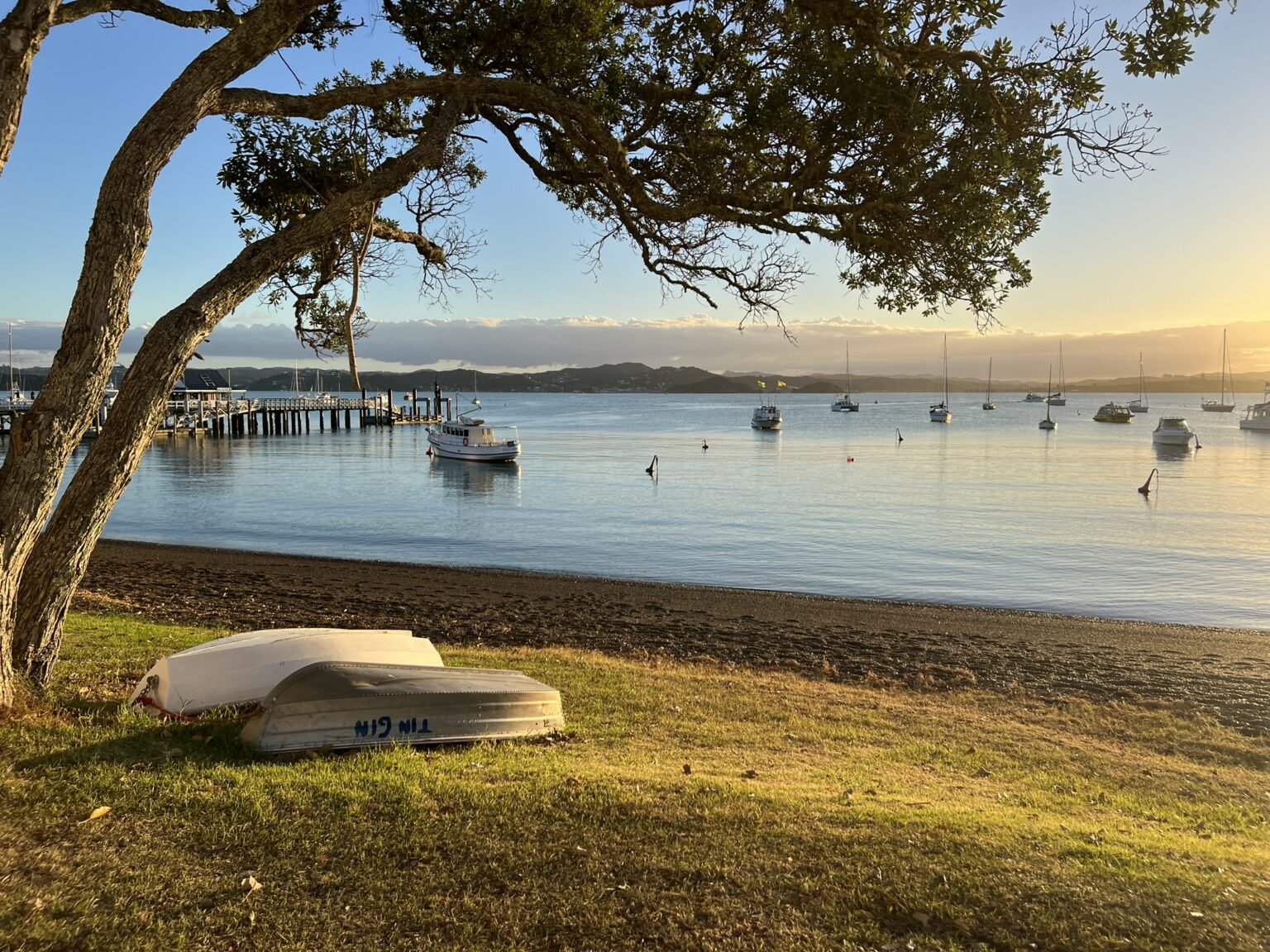the sun setting over a bay with boats in it