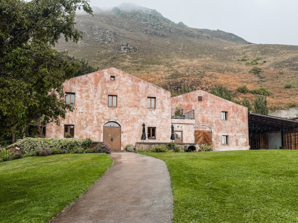 A pink building in front of a mountain in the wine regions of New Zealand