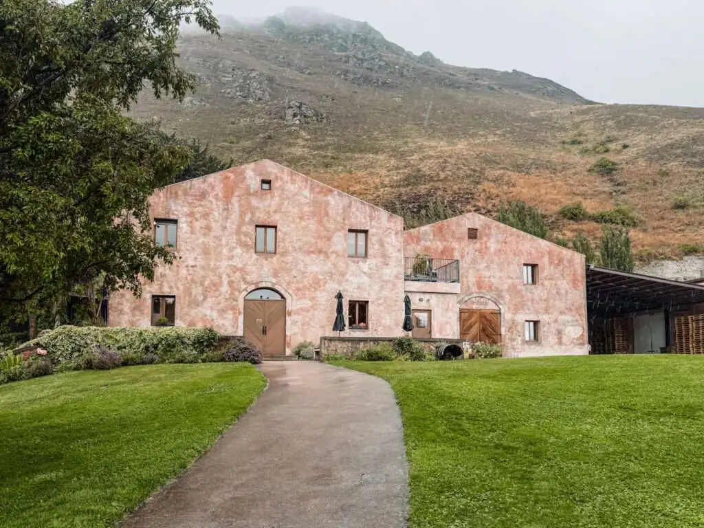 A pink building in front of a mountain in one of the wine regions in New Zealand