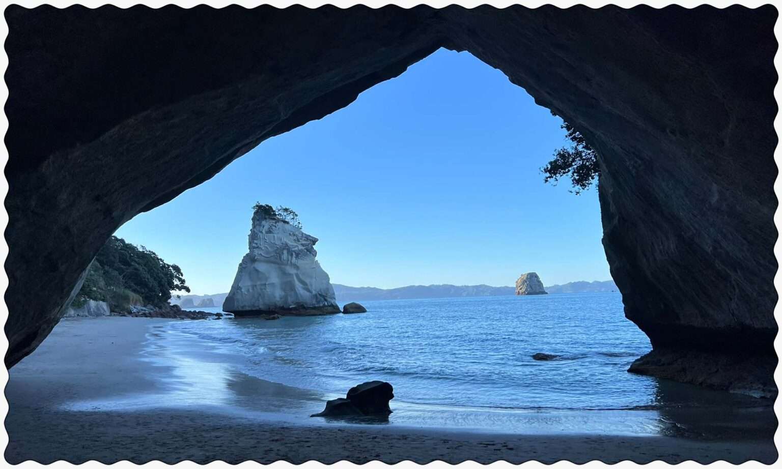 A view through a cave of a rock formation in the water of the Coromandel Peninsula