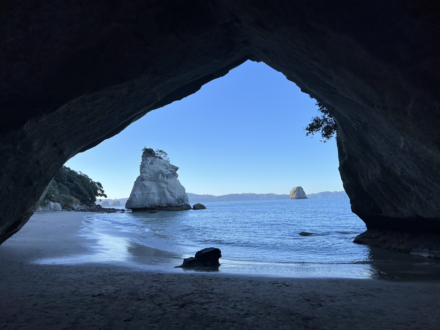 A view through a cave of a rock formation in the water of the Coromandel Peninsula