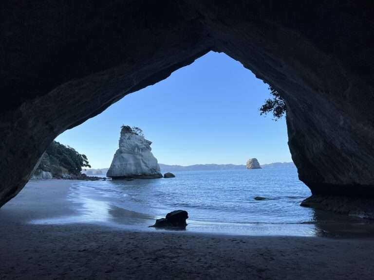 A view through a cave of a rock formation in the water of the Coromandel Peninsula