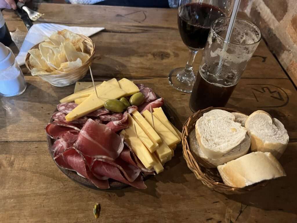 A charcuterie plate along with some bread and drinks - Argentina food and drinks