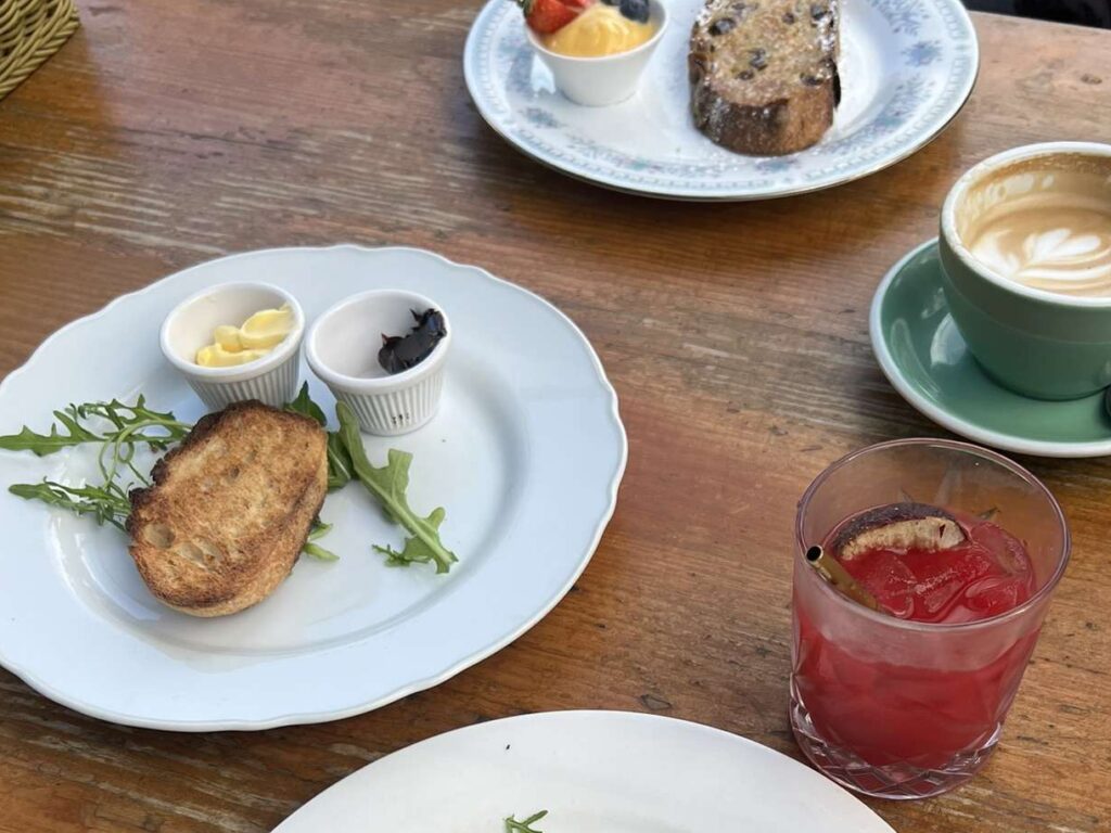 A plate of toast with spreads next to it along with a juice and coffee - australia food and drinks