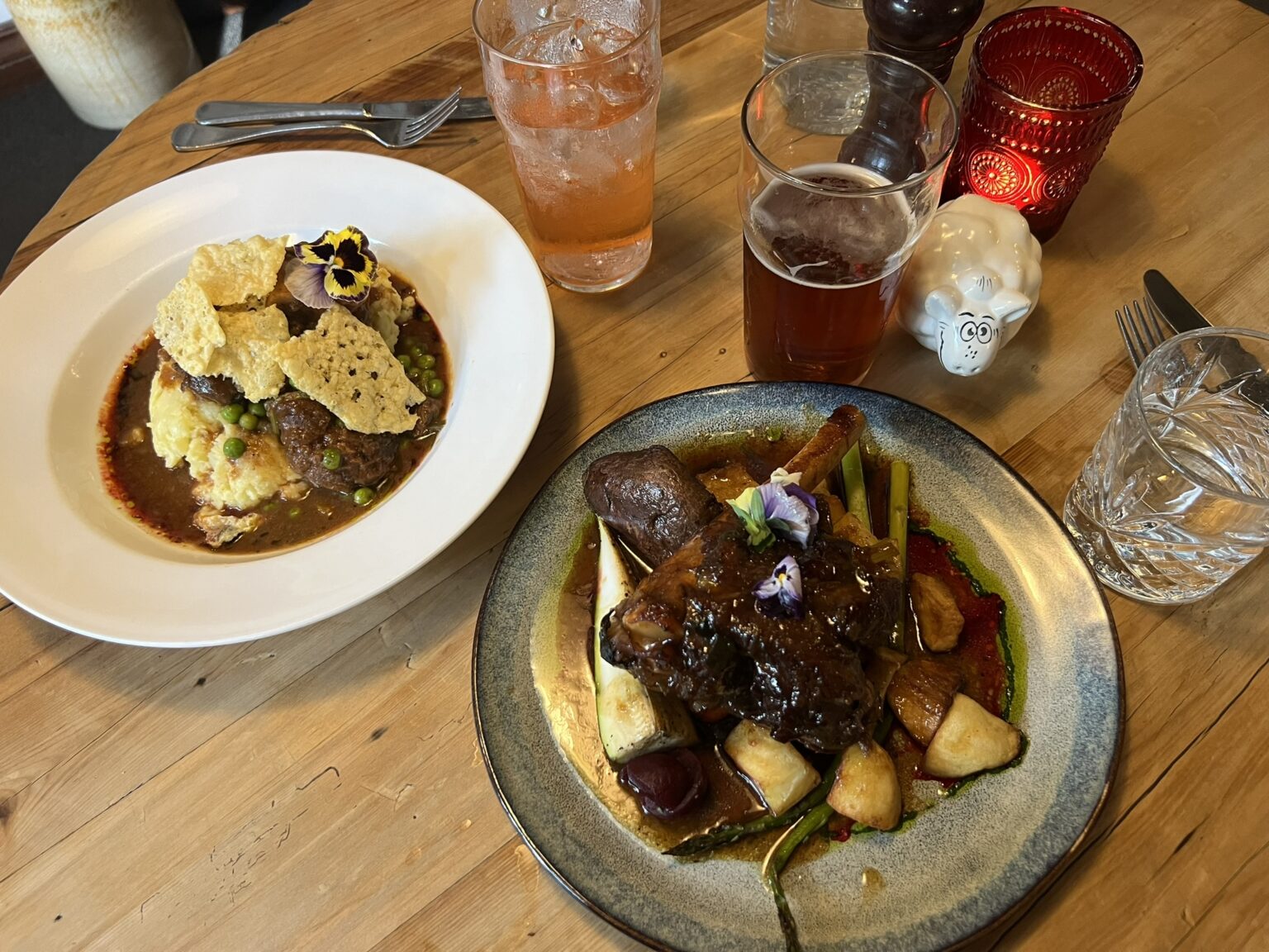 A table with two meals of lamb on a table of popular New Zealand food and drinks