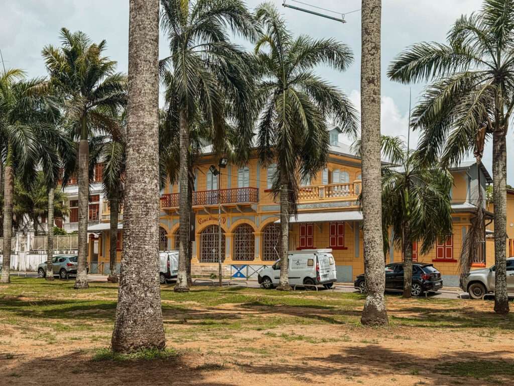 A colonial buildings behind a park of palm trees as part of the French Guiana itinerary