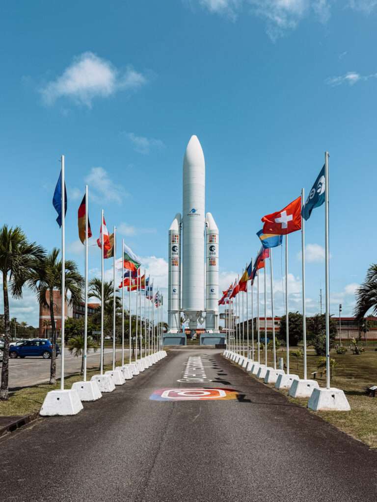 A road lined with flags leading to a rocket as one of the things to do in Kourou