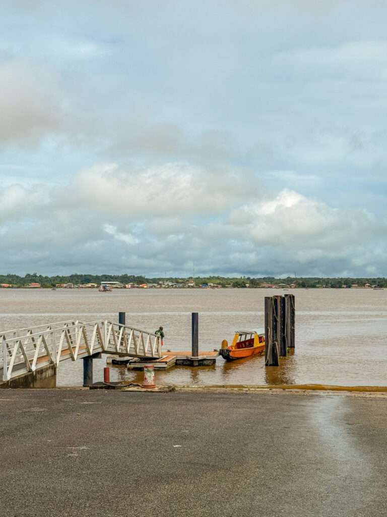 A wooden pirogue waiting at a dock in a river to cross the border between French Guiana and Suriname