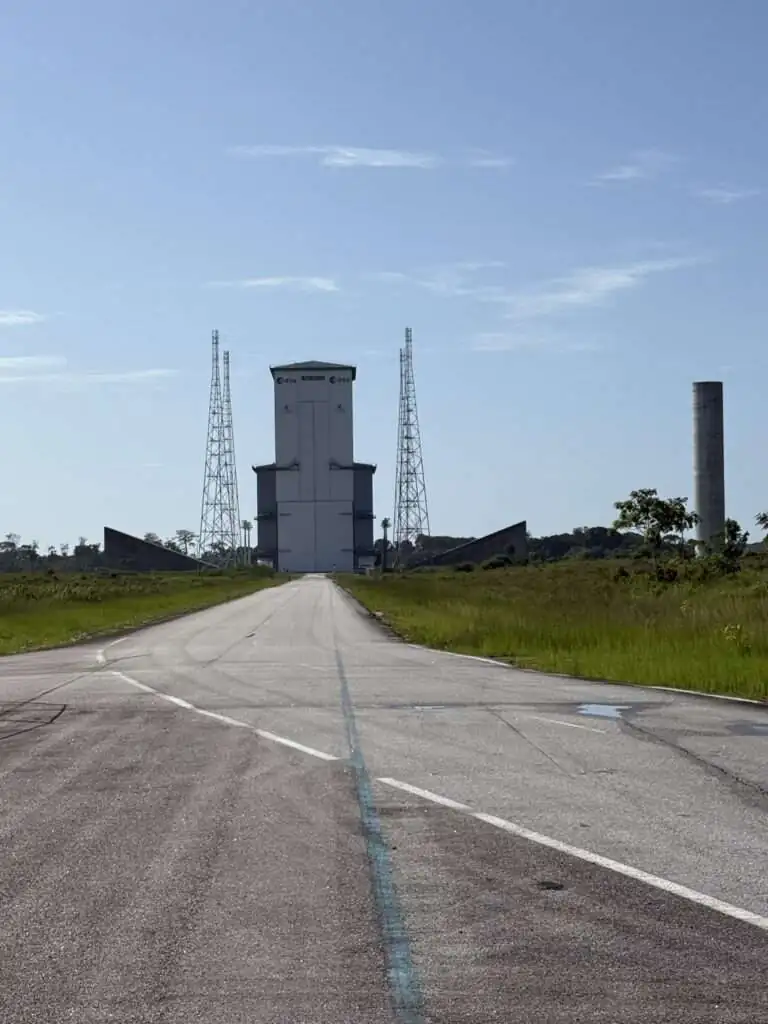 A road to a very tall building out of which rockets are launched in French Guiana