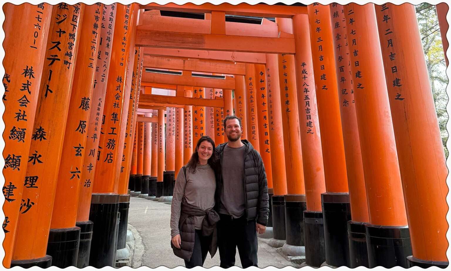 Two people standing in the walkway under a pathway of red gates