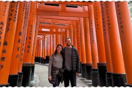Two people standing in the walkway under a pathway of red gates