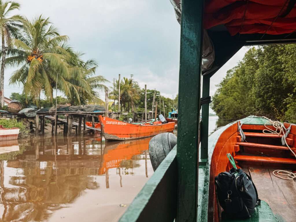 A wooden boat going through some canals with some other boats on a brown river as part of a Suriname itinerary