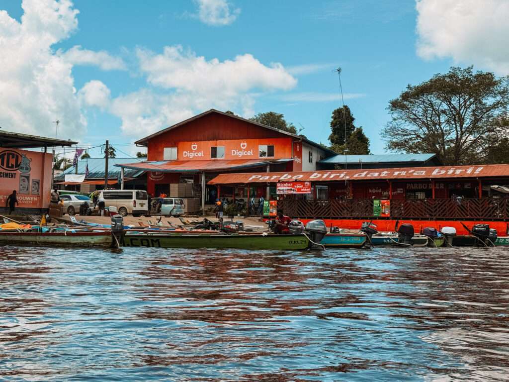 A grouping of pirogue boats at a dock on a river to get to a maroon community as part of the Suriname itinerary