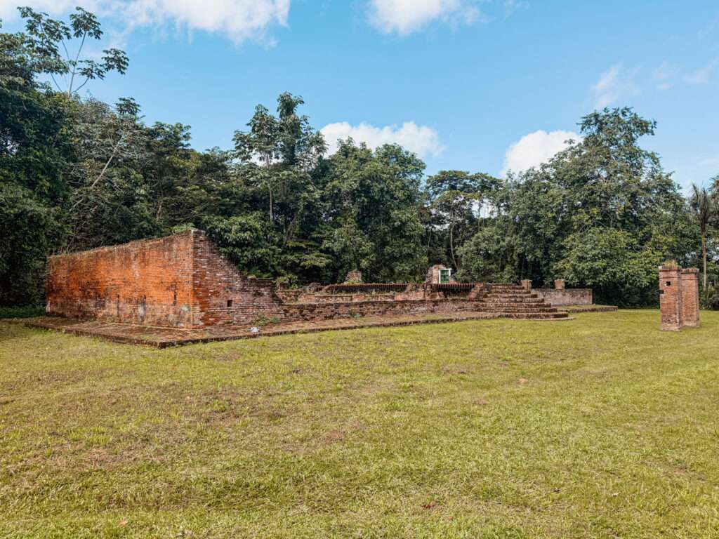The ruins of a brick building on a field as seen in a Suriname itinerary
