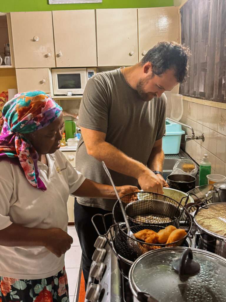 A man and woman cooking in the kitchen making local Surinamese cuisine