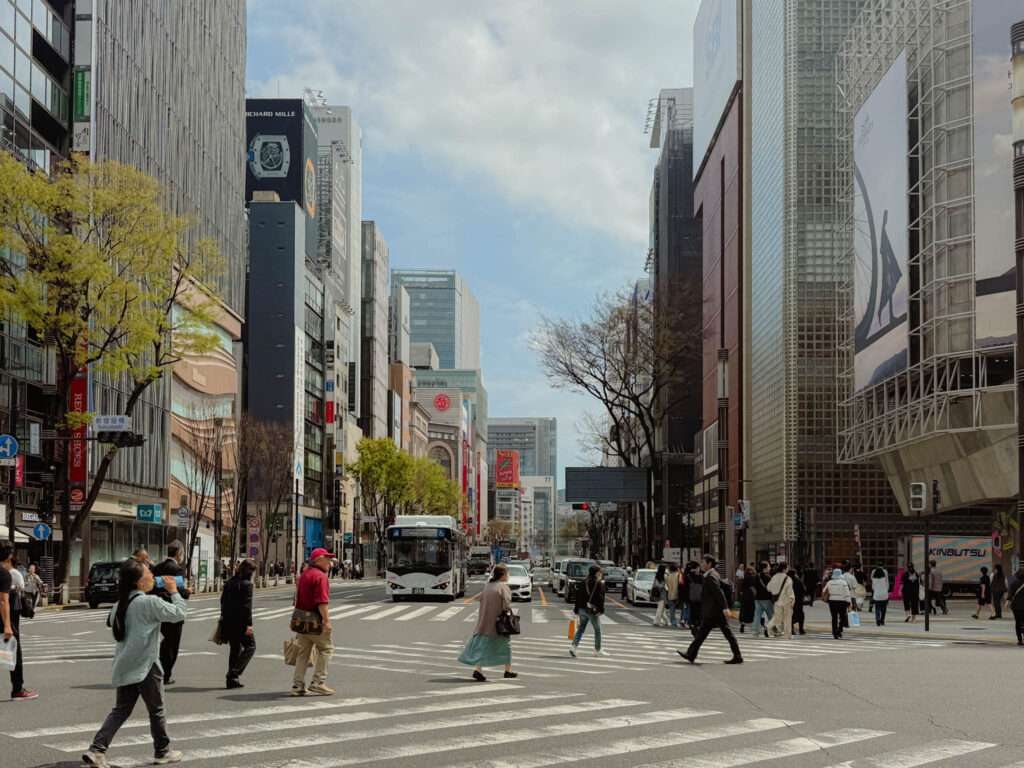 People walking beneath the large city buildings of Ginza in Tokyo, Japan